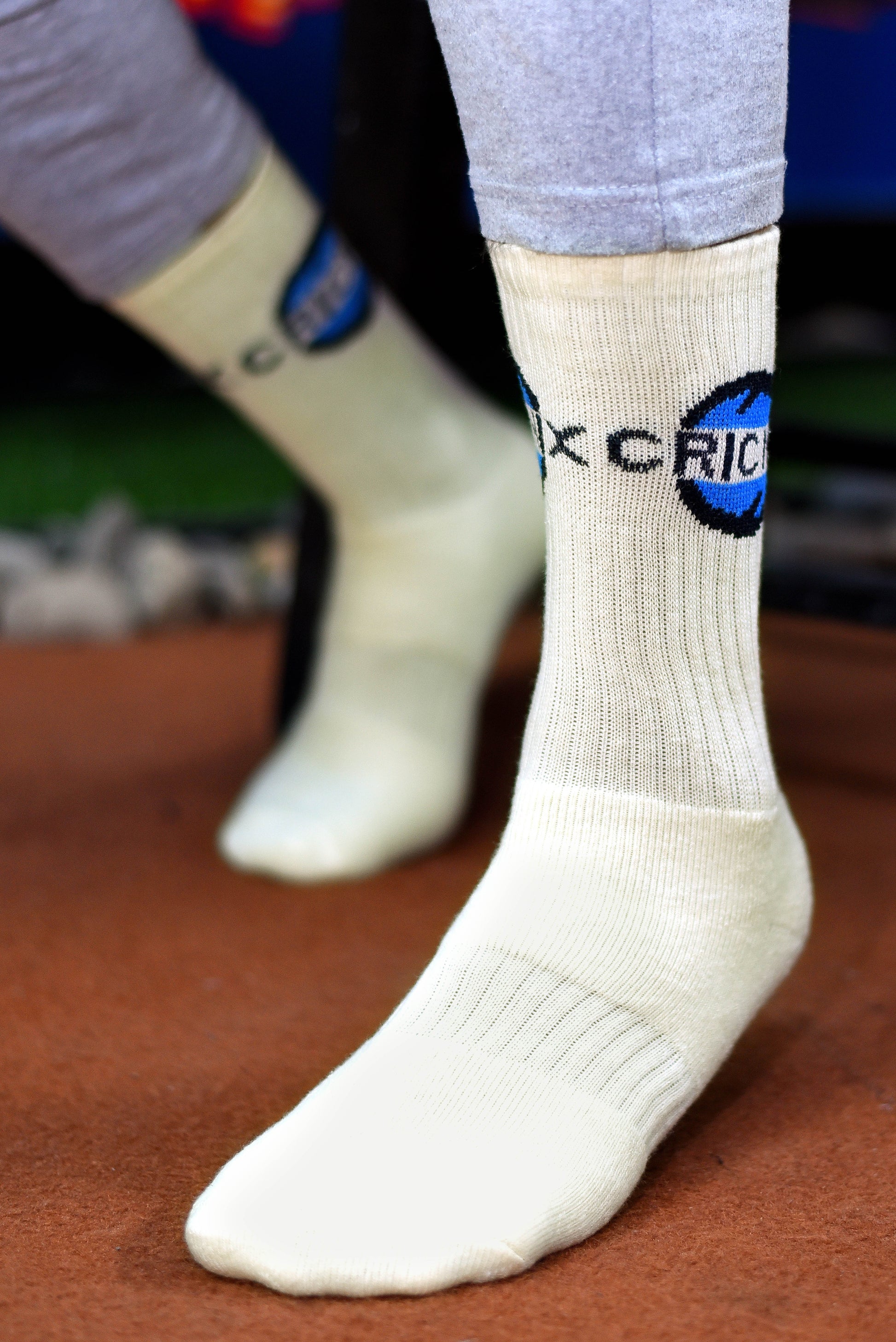 Cricnix sports socks in white with blue and black Cricnix branding, worn by a player on a field.
