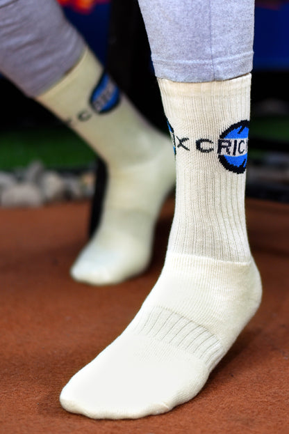 Cricnix sports socks in white with blue and black Cricnix branding, worn by a player on a field.